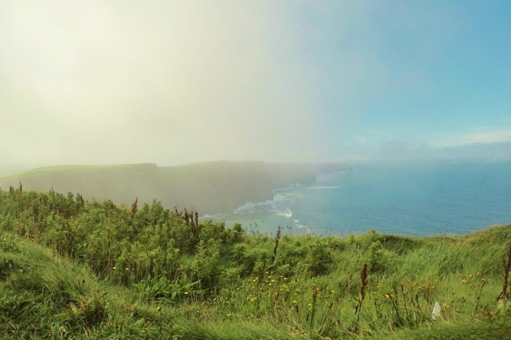 Do precipício gramado é possível ver rochas, uma atrás da outra, formando Cliffs of Moher