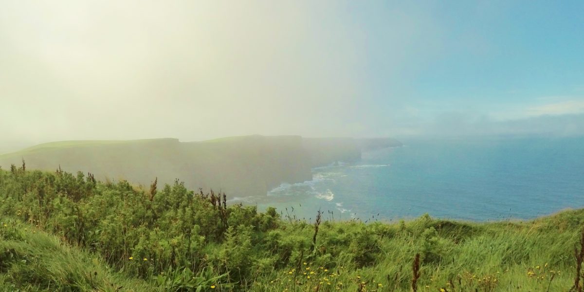 Do precipício gramado é possível ver rochas, uma atrás da outra, formando Cliffs of Moher